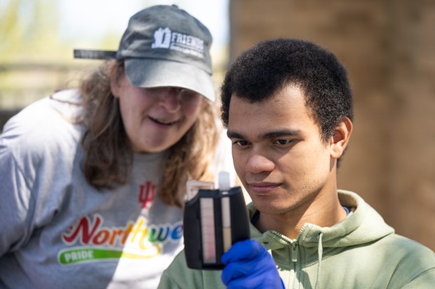 Incoming student Christian Perry, of Merrillville, takes a reading of nitrate content in water from the lagoon at Marquette Park with help from College of Arts and Sciences associate dean and geologist Kris Huysken as they participate in Indiana University Northwest's Summer Bridge program for incoming students on Tuesday, Aug. 13, 2024. (Kyle Telechan/for the Post-Tribune)