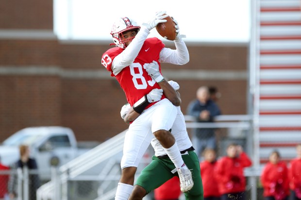 South Elgin's Ishmael George (83), makes a catch as Lane Tech's TJ Harper defends during a Class 8A first-round playoff game in South Elgin on Saturday, Oct. 28, 2023.