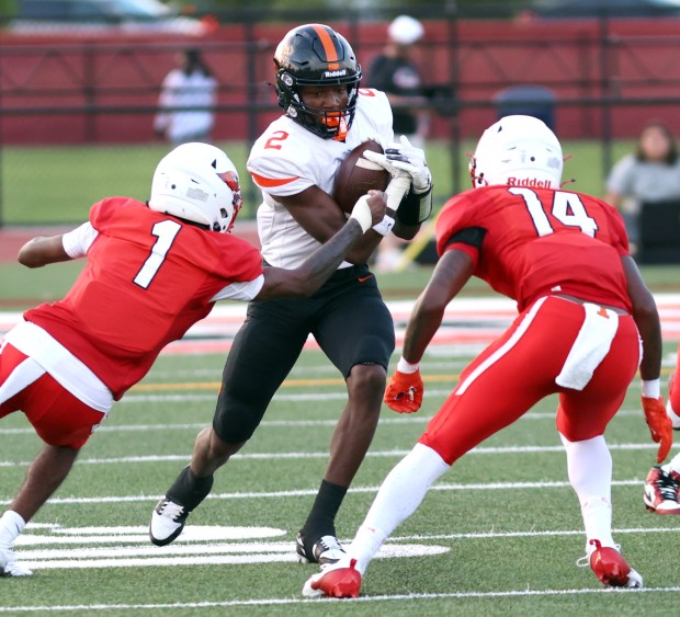 Lincoln-Way West's Jahan Abubakar gains yards as Eisenhower's as Khamarion Wade and Andre Lovett defend during football game in Blue Island on Friday, Aug. 30, 2024. (James C. Svehla / Daily Southtown)