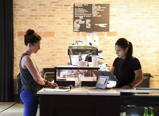 Barista Daniella Martinez, right, helps Kellyn Moran with her order at Froth, a coffee shop inside The Duncan apartment building, in the West Loop on Aug. 5, 2024. (Eileen T. Meslar/Chicago Tribune)