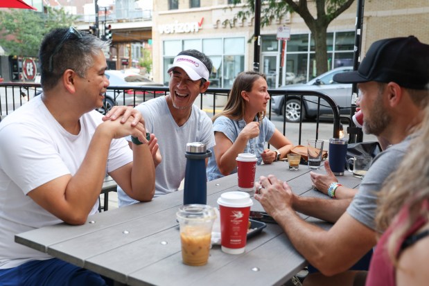 Ryan Mak, second from left, visits with Michael Antiporta, left, at Bitter Pops after dropping their children off for their first day of school at Hamilton Elementary School in Lake View Monday, Aug. 26, 2024. (Eileen T. Meslar/Chicago Tribune)