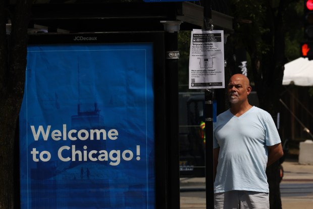 A man reads a CTA temporary reroute sign while waiting for a bus across the street from the United Center as work continues in preparation for the Democratic National Convention Aug. 14, 2024, in Chicago. (John J. Kim/Chicago Tribune)