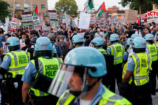 Protesters march past police in helmets in park #578 during the final day of the Democratic National Convention Thursday Aug. 22, 2024, in Chicago. (Armando L. Sanchez/Chicago Tribune)