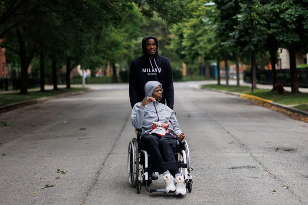 Dion Salley, 23, pushes his brother Davon Salley, 23, in a wheel chair to their home in Chicago Housing Authority's Westhaven Park near the United Center on Tuesday, Aug. 6, 2024, in Chicago. Westhaven Park was built in place of the Henry Horner public housing complex. (Armando L. Sanchez/Chicago Tribune)