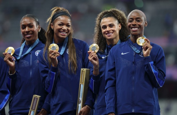 USA's Shamier Little, right, and her Olympic women's 4x400-meter relay teammates Alexis Holmes, Gabby Thomas and Sydney McLaughlin-Levrone receive their gold medals Saturday, Aug. 10, 2024, at Stade de France in Paris. (Brian Cassella/Chicago Tribune)