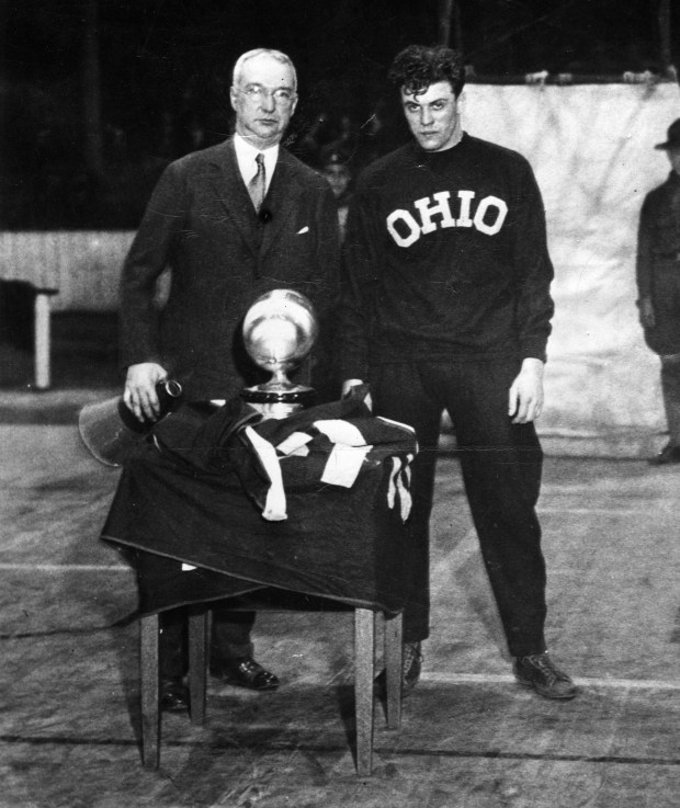 Harvey Woodruff, Tribune sports writer, left, presents Wesley Fesler of Ohio State, the Chicago Tribune Silver Football trophy between halves of the Ohio State vs Wisconsin basketball game at Columbus, circa Jan. 14, 1931. (Chicago Tribune archive)