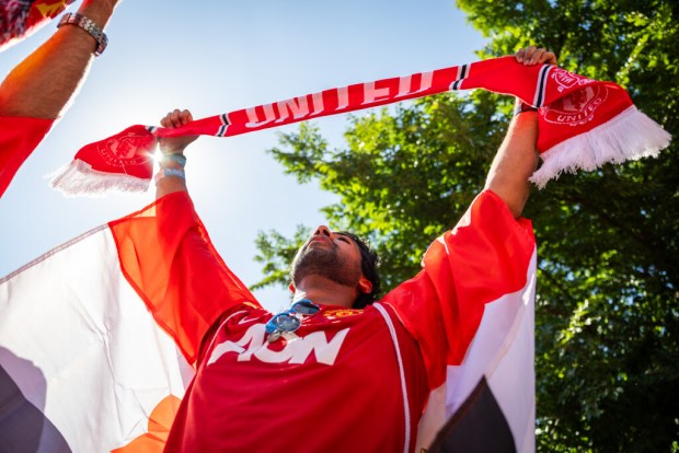 Manchester United fan Ayuji Prasad holds up their scarf before the start of a soccer match between Manchester United and Crystal Palace at the Premier League Mornings Live Fan Fest in the Lincoln Park neighborhood of Chicago on Sept. 21, 2024. (Tess Crowley/Chicago Tribune)