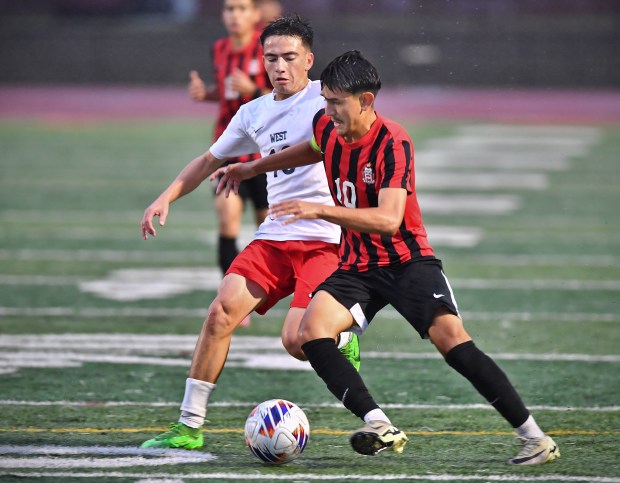 East Aurora's Asbel Vazquez (right) tries to advance the ball as West Aurora's Carlos Gracia Sheets defends during a game on Tuesday, Sept. 24, 2024 in Aurora...(Jon Cunningham/for The Beacon-News)