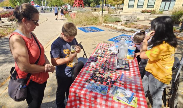 Tiffany Warmowski of Oakbrook Terrace and her son Nico, 10, stop by to decorate a few rocks Saturday for the new Peace Garden in Batavia. (David Sharos / For The Beacon-News)