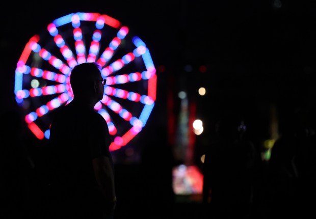 With a Ferris wheel in the background, a fest-goer takes in the performance of Foo Fighters at Riot Fest in Chicago's Douglass Park on Sept. 15, 2023. What is Riot Fest but three days of music for audiences that may have reached the autumn of their festival-going? (Chris Sweda/Chicago Tribune)