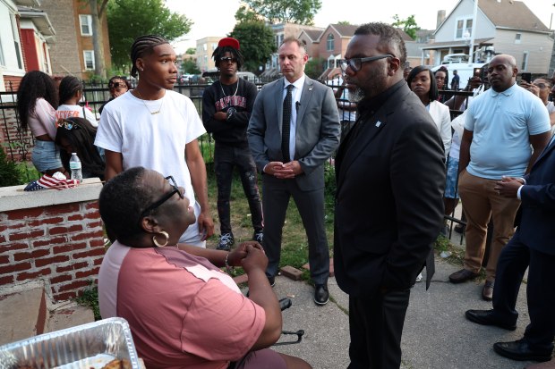 Chicago Mayor Brandon Johnson, right meets with Toni Strong Upshaw, seated, in the 7100 block of S. Woodlawn Avenue in Chicago on Friday, July 5, 2024, after a vigil for some of Upshaw's descendants who were shot and fatally wounded in the block a day earlier. Upshaw criticized the mayor and the police department but later apologized for her comments. Johnson said she had no need to apologize. (Terrence Antonio James/Chicago Tribune)