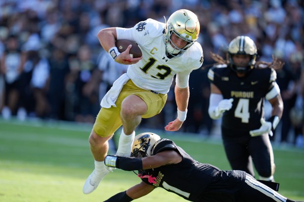 Notre Dame quarterback Riley Leonard goes over Purdue defensive back Markevious Brown for a touchdown on Sept. 14, 2024, in West Lafayette, Ind. (AP Photo/Michael Conroy)