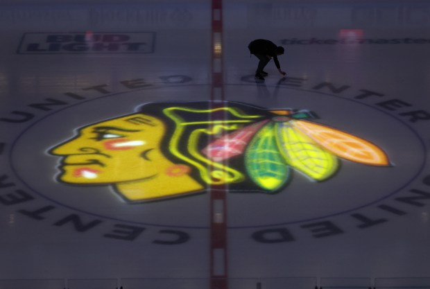 The center ice Blackhawks logo is illuminated as a worker inspects the United Center ice before a game against the Kings on March 15, 2024. (John J. Kim/Chicago Tribune)