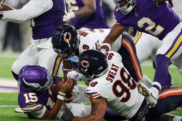 Chicago Bears safety Jaquan Brisker (9) and Chicago Bears defensive end Montez Sweat (98) sack Minnesota Vikings quarterback Joshua Dobbs (15) during the third quarter at U.S. Bank Stadium in Minneapolis Nov. 27, 2023. (Eileen T. Meslar/Chicago Tribune)