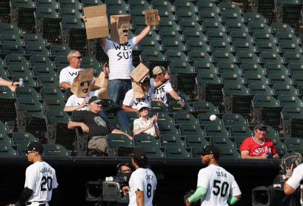 A group of fans wear matching T-shirts and paper bags over their heads show their disappointment as White Sox players head to the dugout in the middle of the ninth inning against the Guardians at Guaranteed Rate Field on Sept. 11, 2024, in Chicago. (John J. Kim/Chicago Tribune)