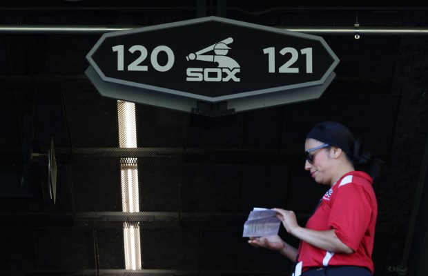 A guest services worker stands under a sign for sections 120 and 121 before the final home game for the White Sox against the Angles at Guaranteed Rate Field on Sept. 26, 2024, in Chicago. The White Sox are tied with the Mets for most games lost in a season in the modern era at 120 and could break the record today with 121 losses. (John J. Kim/Chicago Tribune)