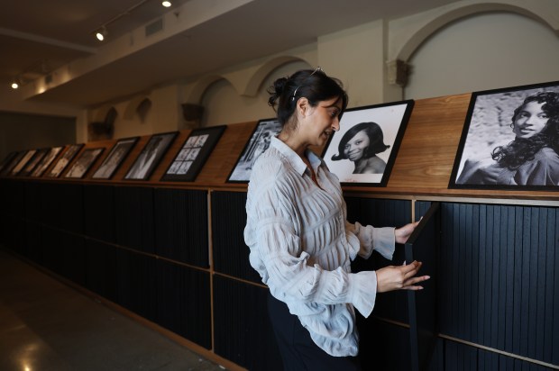 Sabina Bokhari, director of special projects at the Theaster Gates Studio and Foundation, describes the kinds of photographs included in a piece titled, "Facsimile Cabinet of Women Origin Stories," as part of the exhibition, "When Clouds Roll Away: Reflection and Restoration from the Johnson Archive," at the Stony Island Arts Bank. (John J. Kim/Chicago Tribune)