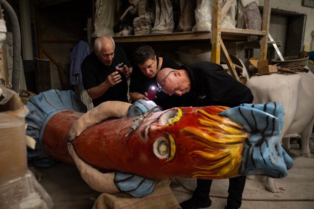 Superdawg Drive-In co-owners Scott Berman, from left, Lisa Drucker and Don Drucker admire the original chicken wire and paper-mache armature inside Flaurie, one of the restaurant's rooftop mascot figures undergoing restoration at Orlandi Statuary in Logan Square, on Sept. 24, 2024. (E. Jason Wambsgans/Chicago Tribune)