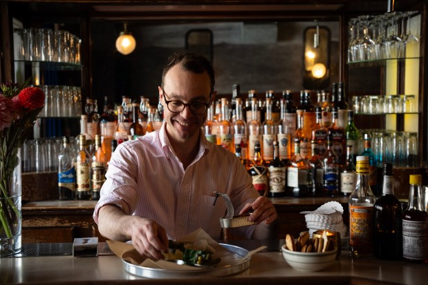 Queen Mary Tavern general manager Dan Smith plates an arrangement of tinned seafood offerings at the Ukrainian Village cocktail bar, Aug. 14, 2024. (E. Jason Wambsgans/Chicago Tribune)