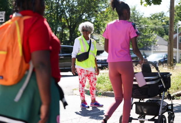 Safe Passage worker Denise Evans helps people cross Normal Avenue at 124th Street outside Metcalfe Community Academy in West Pullman after school on Wednesday, Sept. 4, 2024. (Eileen T. Meslar/Chicago Tribune)