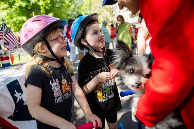 Lizzie Limestall, 6, left, and brother Alex Limestall, 6, center, pet Julia Sibley's dog Kingsley, right, before the start of the WOOGMS parade in the Lakeview neighborhood of Chicago on Sept. 2, 2024. (Tess Crowley/Chicago Tribune)