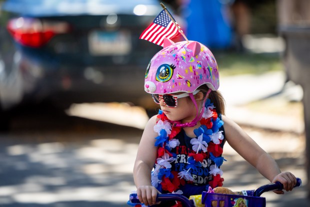 Zoey Heberling, 5, bikes to the start of the WOOGMS parade in the Lakeview neighborhood of Chicago on Sept. 2, 2024. (Tess Crowley/Chicago Tribune)