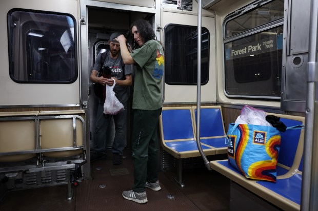 Katie Rafferty brushes her hair as Richard Smith organizes their belongings after boarding a train at the CTA Forest Park Blue Line station on Sept. 5, 2024. The two are homeless and avoid sleeping on CTA trains because of safety concerns. (John J. Kim/Chicago Tribune)