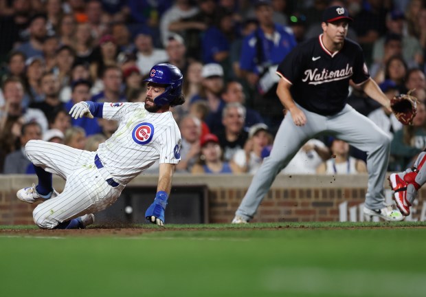 Chicago Cubs shortstop Dansby Swanson slides in safely at home plate while scoring on a sacrifice fly by teammate Isaac Paredes in the fifth inning of a game against the Washington Nationals at Wrigley Field in Chicago on Sept. 19, 2024. (Chris Sweda/Chicago Tribune)