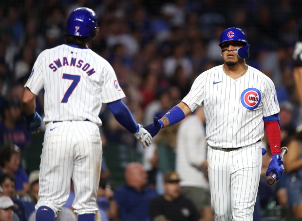 Cubs shortstop Dansby Swanson is congratulated by third baseman Isaac Paredes after scoring in the first inning against the Nationals on Sept. 19, 2024, at Wrigley Field. (Chris Sweda/Chicago Tribune)