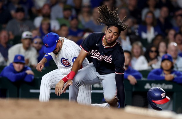 Nationals left fielder James Wood loses his helmet as he advances on a wild pitch as Cubs third baseman Isaac Paredes makes a late catch in the third inning on Sept. 19, 2024, at Wrigley Field. (Chris Sweda/Chicago Tribune)