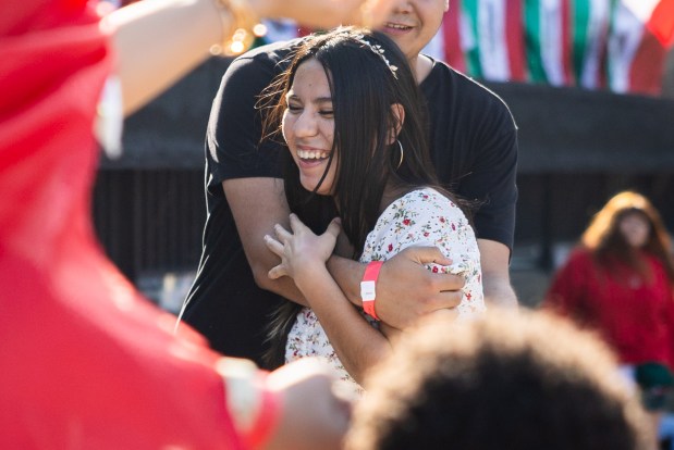 Sebastian Aguilar, from Chicago, back, embraces girlfriend Citlali Hernandez, from Indiana, center, after a dance at El Grito Chicago, a two-day festival in celebration of Mexican Independence Day, at Grant Park's Butler Field in Chicago on Sept. 14, 2024. (Tess Crowley/Chicago Tribune)