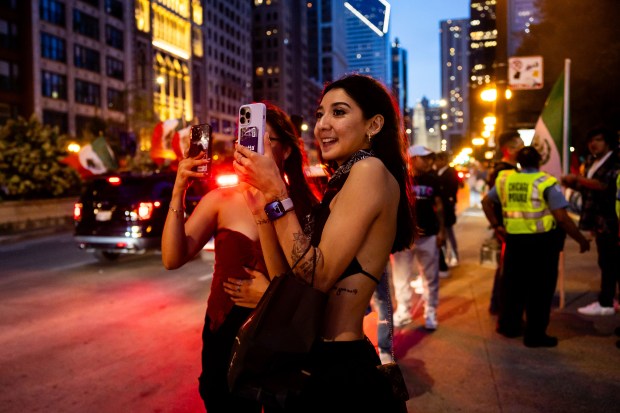 Crystal Barron, from Colorado, center, and friend Samantha Guardian, from Colorado, left, watch as cars ride down Michigan Avenue in celebration of Mexican Independence Day in Chicago on Sept. 14, 2024. They traveled to Chicago to witness the celebration. (Tess Crowley/Chicago Tribune)