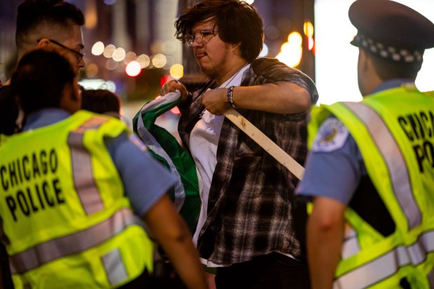 A person is stopped by police on Michigan Avenue and told to remove their Mexican flag from its stake during a celebration of Mexican Independence Day in Chicago on Sept. 14, 2024. (Tess Crowley/Chicago Tribune)