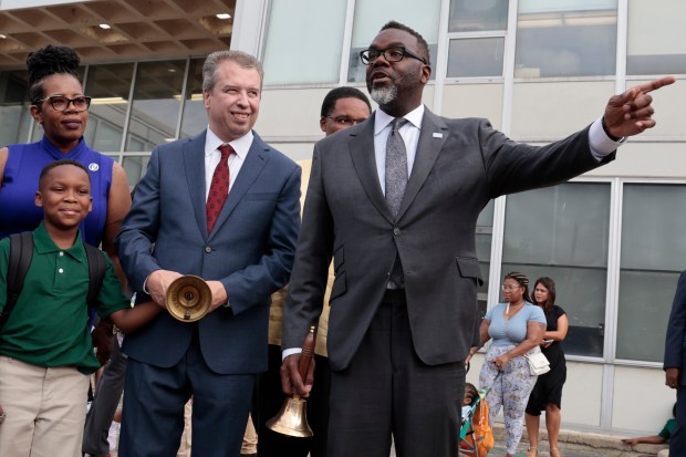 Mayor Brandon Johnson, right, and Chicago Public Schools CEO Pedro Martinez prepare to ring the bells to welcome students back to school at Chalmers Elementary Specialty School on Aug. 26, 2024. (Antonio Perez/Chicago Tribune)