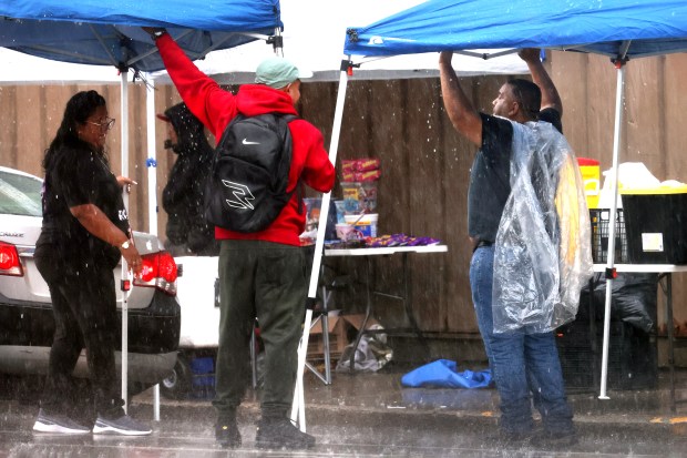 Shoppers and vendors try to drain and move the covered shelters during a rainy day on Tuesday, Sept. 24, 2024. (Antonio Perez/Chicago Tribune)