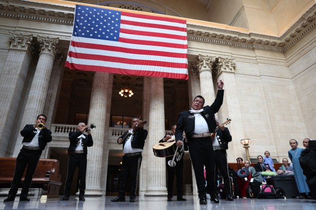 Ramiro Zamora leads other members of the Mariachi band Los Palmeros inside the Great Hall of Chicago's Union Station on Wednesday, Sept. 18, 2024. The band was on hand to entertain during an event honoring the legacy of Latino railroad workers at Amtrak and in Illinois. At right are members of 5 families from Fremont, Michigan, who are traveling through Union Station en route to Montana. (Chris Sweda/Chicago Tribune)