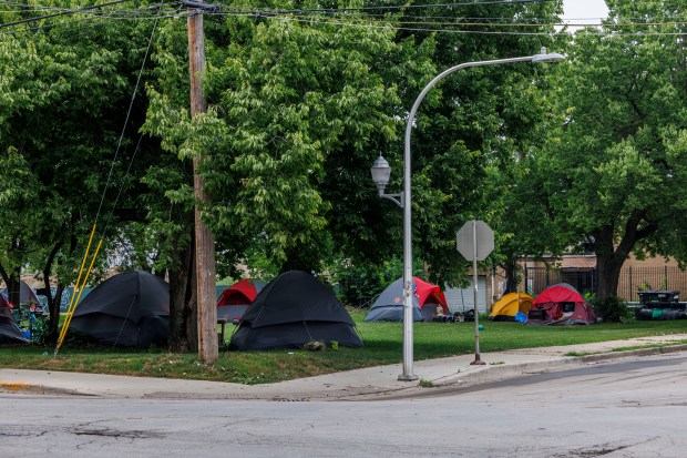 A group of migrants from Venezuela shelter in tents among other homeless in a field several blocks from the 12th District Chicago Police Station on Friday Aug. 2, 2024, in Chicago. (Armando L. Sanchez/Chicago Tribune)