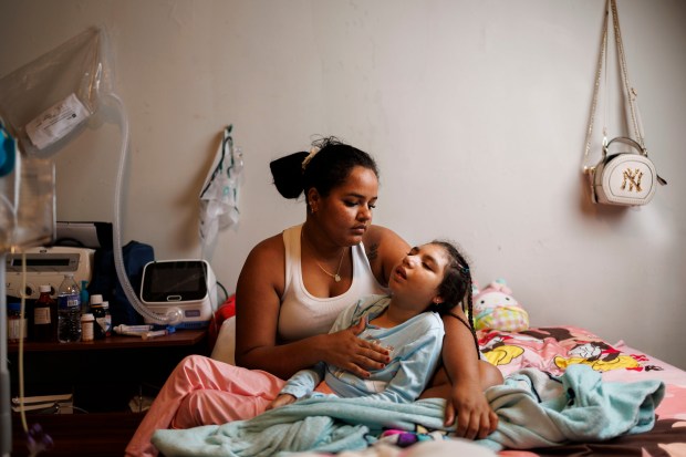 Yamile Perez, 28, holds her daughter Keinymar Avila, 8, while posing for a portrait in their home in the South Shore neighborhood of Chicago on Aug. 7, 2024. Avila has microcephaly a condition where a baby's head is smaller than normal causing seizures, developmental delays and intellectual disability.(Armando L. Sanchez/Chicago Tribune)