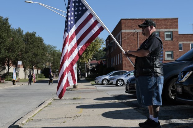 Tim Nelson, of Wisconsin, holds a flag to honor former Chicago police Officer James Crowley and his family before the start of the funeral procession to St. Christina Church on Sept. 4, 2024. (Antonio Perez/Chicago Tribune)