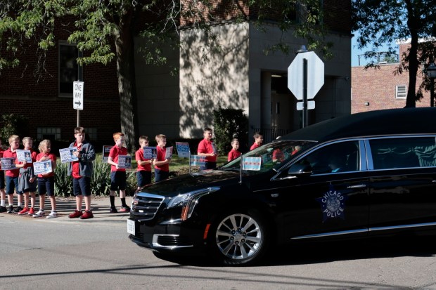 Students from St. Christina School hold placards with the image of former Chicago police Officer James Crowley as the hearse carrying his casket travels to St. Christina Church for his funeral on Sept. 4, 2024. (Antonio Perez/Chicago Tribune)