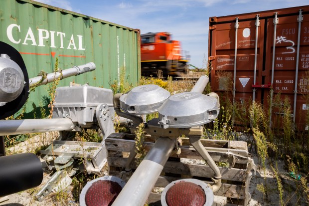 Railroad crossing safety equipment is seen on the ground near tracks as a train passes near the intersection of 147th and Wood Streets in Harvey on Sept. 13, 2024. (Tess Crowley/Chicago Tribune)