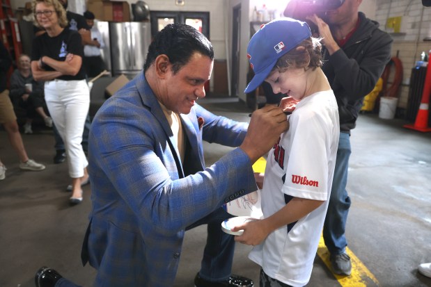 Former Chicago Cubs star player Sammy Sosa autographs a baseball jersey for Ryan Hopkins, 8, (Ald. Hopkins son), at the Chicago Fire Department firehouse Engine 98/Ambulance 11, before presenting a $10,000 donation to charities , EMWQ Retirees, Widows' & Children's Assistance Fund and Light the Line, that supports Chicago Police Department. (Antonio Perez/Chicago Tribune)