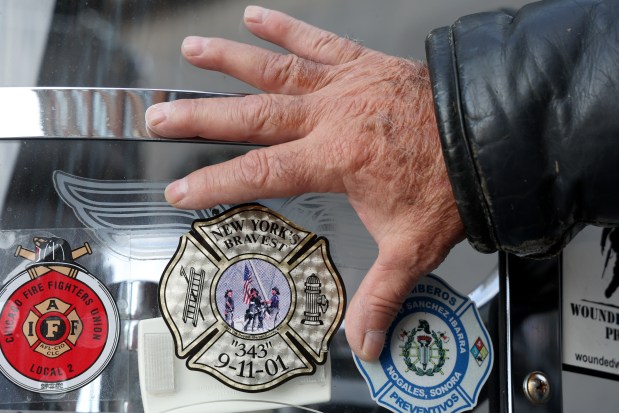 Former Chicago fire department Captain George Rabiela, who volunteered to assist in New York City after 9/11 touches a memorial decal on his motorcycle on Sept. 11, 2024. (Antonio Perez/Chicago Tribune)