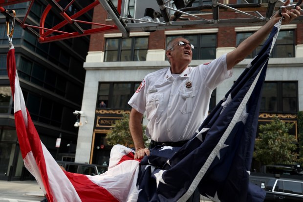 Firefighter George Mac prepares to fold up the American flag following a ceremony marking the 23rd anniversary of the 9/11 terrorist attacks, Sept. 11, 2024, outside the Engine 42 fire station in Chicago. (Antonio Perez/Chicago Tribune)