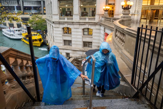 People climb steps from the Chicago River after a Wendella boat tour in heavy rain on Sept. 24, 2024. (Tess Crowley/Chicago Tribune)