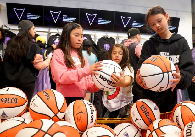 Ellie Ngo, 11, Sabina Cianfrocca, 8, and her sister Verona, 11, check the new Golden State Valkyries basketballs during a block party at Thrive City in San Francisco on May 18, 2024. (Ray Chavez/Bay Area News Group)