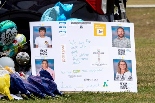 A poster with images of victims Christian Angulo, top left, Richard Aspinwall, top right, Mason Schermerhorn, bottom left, and Cristina Irimie is displayed at a memorial outside Apalachee High School, Friday, Sept. 6, 2024, in Winder, Ga., following a shooting at the school earlier in the week. (Arvin Temkar/Atlanta Journal-Constitution via AP)