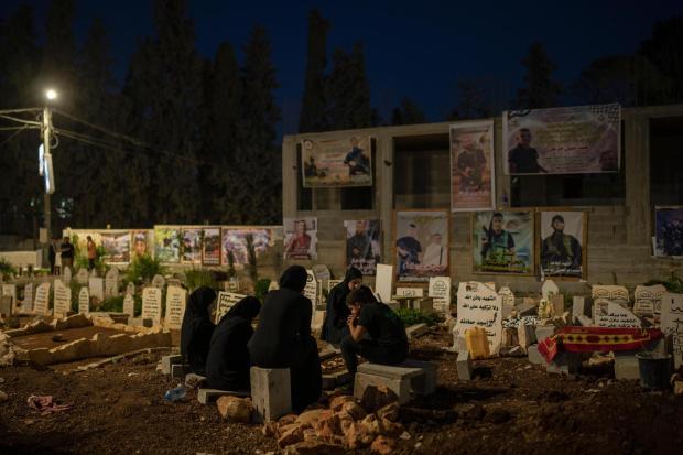 Family members sit next to the grave of Odei, 22, in Jenin, West Bank, Saturday, June 8, 2024. Odei was killed by Israeli forces during a raid inside the Jenin refugee camp. (AP Photo/Bram Janssen)