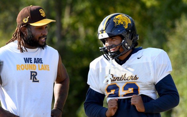 Panther's Elian Barrera shares a laugh with defensive line coach Nick Jones. Round Lake High School's football team prepares for Friday's night's home game against Antioch, Tuesday, Sept. 10, 2024.  (Rob Dicker / News-Sun)