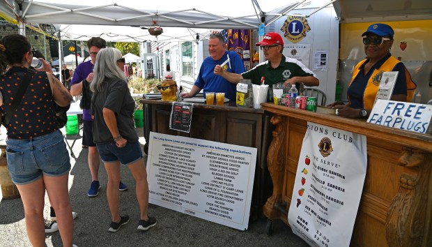 At the Long Grove Lions Club booth, serving beverages, including apple sangria, (center, from left to right), in blue shirt, are Craig Kosik of Buffalo Grove and Mike Kaitson of Lindenhurst at Apple Fest in Long Grove on Sept. 21, 2024. (Karie Angell Luc/Lake County News-Sun)